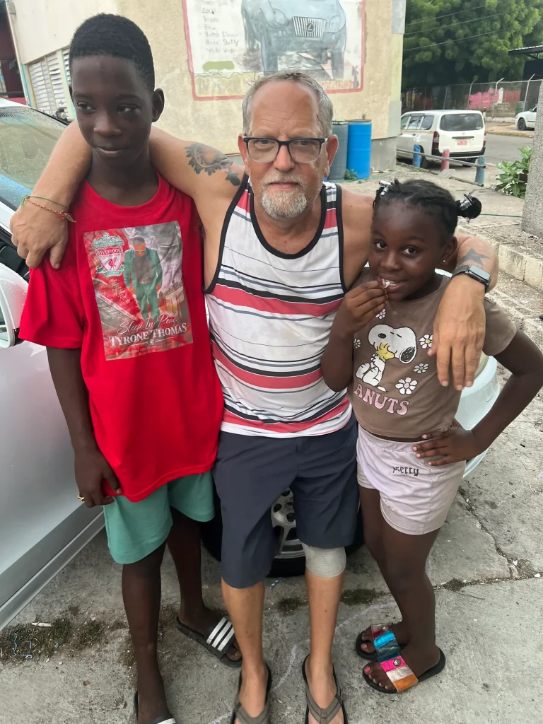 Darrell posing with two children during the Give Back in Trench Town, Jamaica.